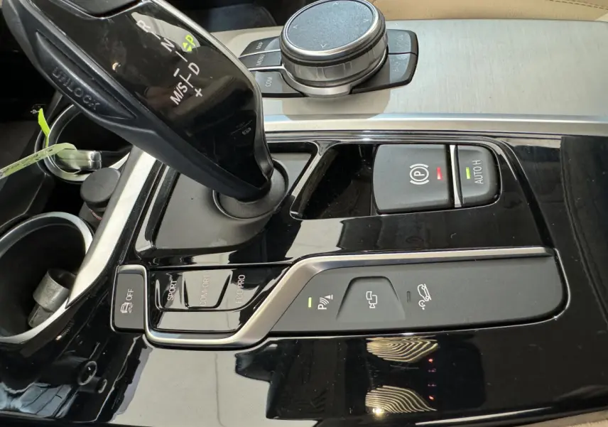 Gros plan sur la console centrale noire brillante du BMW X3 xDrive30d, montrant levier de vitesses et commandes de conduite.