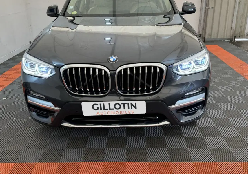 Vue frontale rapprochée du BMW X3 gris foncé avec phares LED allumés et calandre double haricot distinctive.