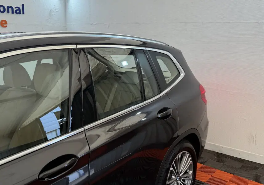 Vue latérale arrière droite d'un BMW X3 gris foncé avec jantes alliage et vitres teintées dans un garage.