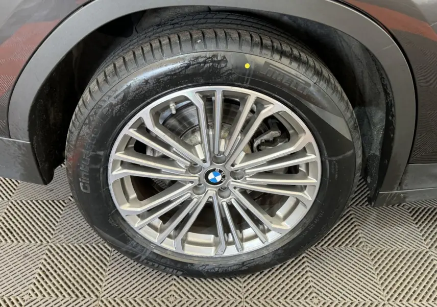 Gros plan sur la roue avant droite d'un BMW X3 gris foncé, mettant en valeur la jante alliage multi-branches et le pneu.