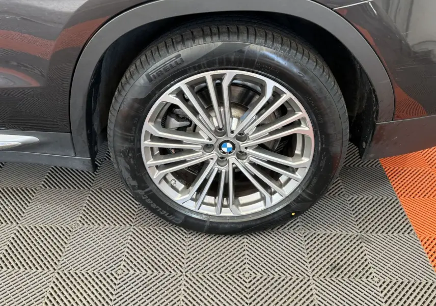 Gros plan sur la roue arrière droite d’un BMW X3 gris foncé avec jante alliage multi-branches et pneu Pirelli.