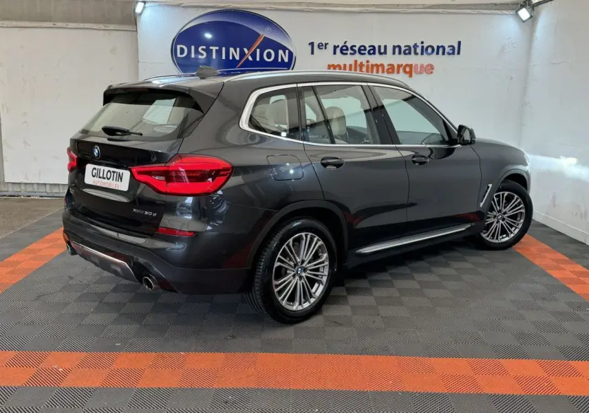 BMW X3 xDrive30d gris foncé vu en 3/4 arrière droit dans un showroom avec jantes alliage et feux LED.