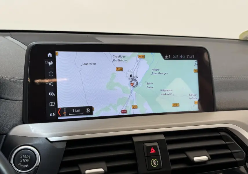 Vue rapprochée de l'écran tactile 10,3 pouces du tableau de bord du BMW X3 gris foncé affichant la navigation GPS.