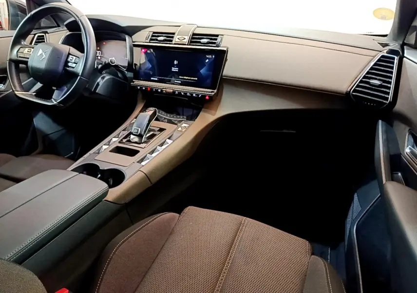 Vue intérieure côté passager du DS7 Crossback 2020, tableau de bord et console centrale en tons marron et noir.
