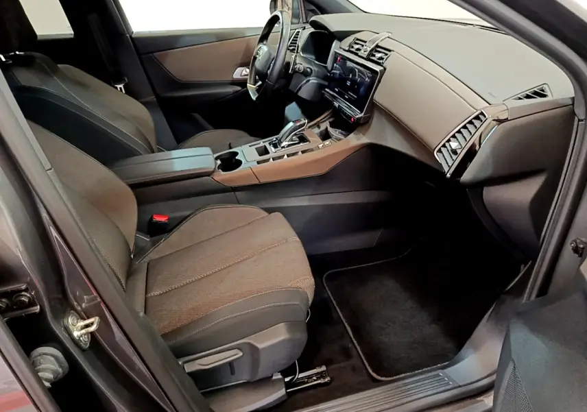 Intérieur avant droit du DS7 Crossback gris foncé, avec tableau de bord moderne et sièges tissu noirs.