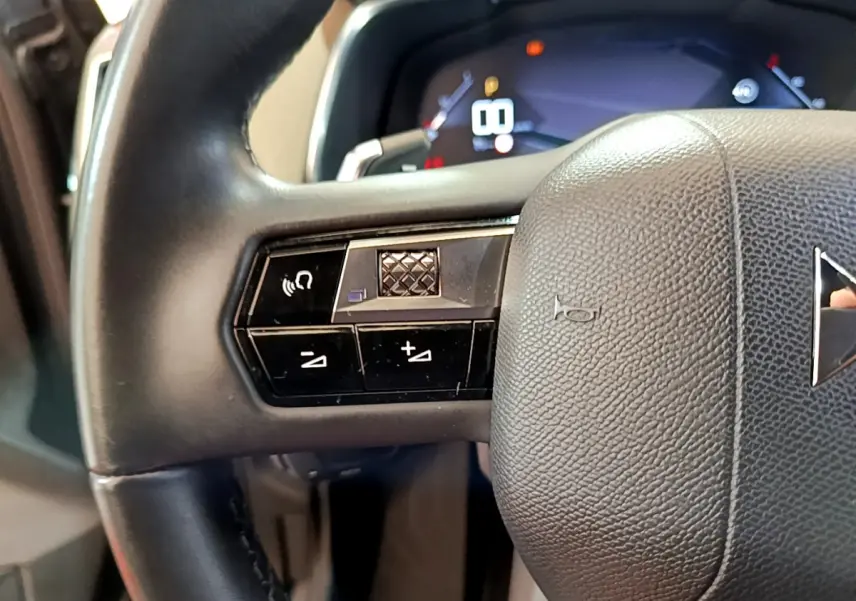 Gros plan sur le volant cuir noir du DS7 Crossback 2020, avec commandes intégrées et tableau de bord numérique en arrière-plan.