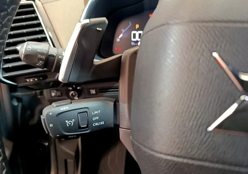 Gros plan sur la commande de régulateur de vitesse à gauche du volant cuir gris foncé du DS7 Crossback 2020.