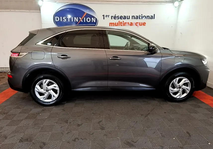 Vue profil droit d'un DS7 Crossback gris foncé 2020 garé en intérieur, soulignant ses lignes élégantes et ses jantes alliage.