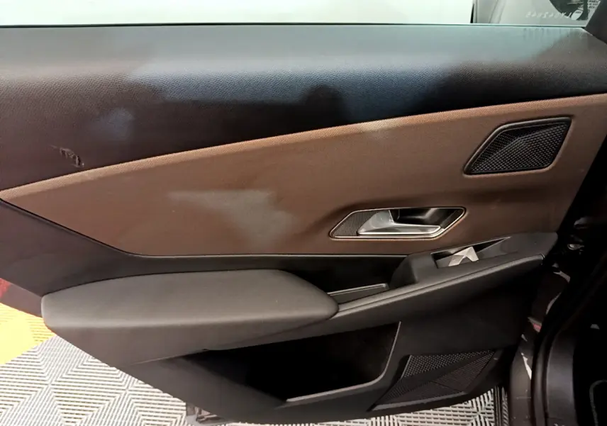 Vue intérieure du panneau de porte avant droit du DS7 Crossback 2020 en gris foncé avec garniture marron et commandes.
