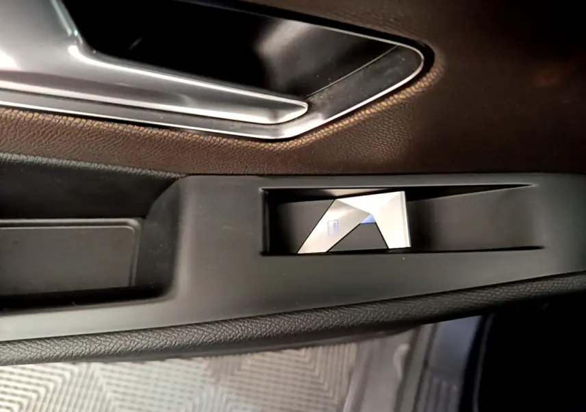 Gros plan sur le bouton de verrouillage centralisé côté gauche, intérieur noir du DS7 Crossback gris foncé.