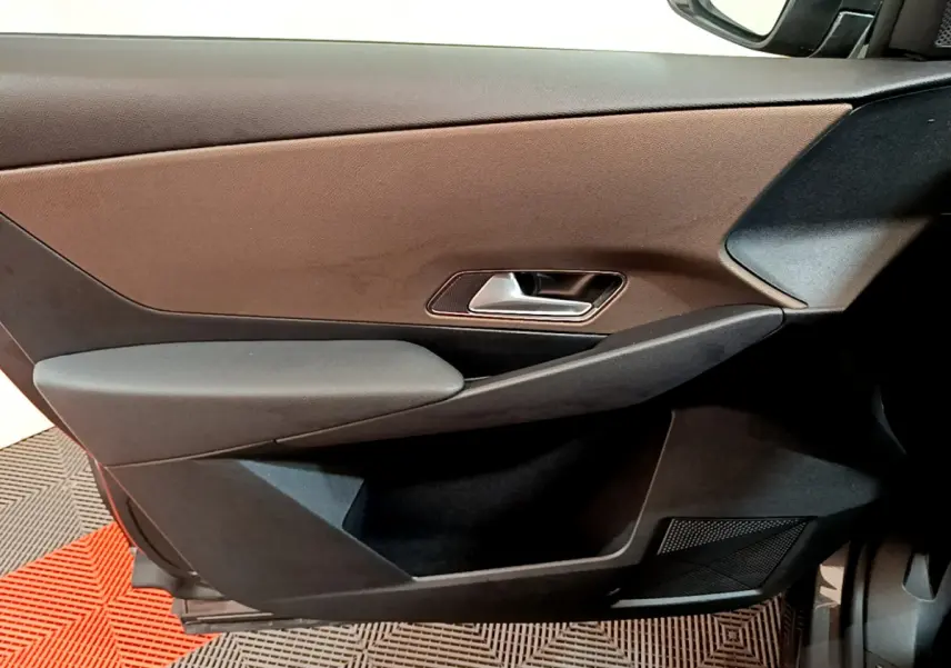 Vue rapprochée de la porte côté droit intérieure du DS7 Crossback gris foncé, avec poignée argentée et panneau bicolore.