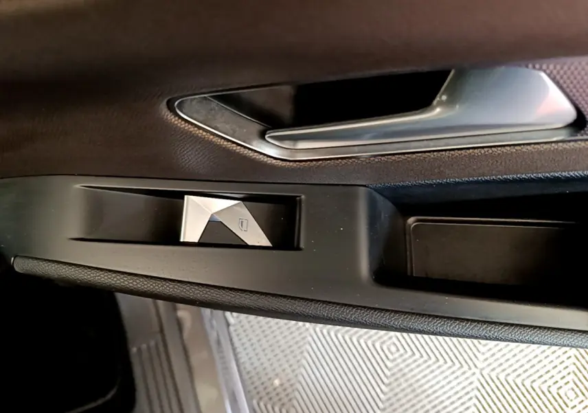 Gros plan sur la poignée intérieure et commande de lève-vitre côté gauche du DS7 Crossback gris foncé.