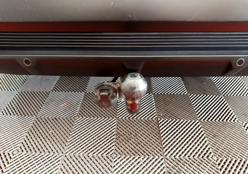 Gros plan sur l'attelage arrière d'un DS7 Crossback gris foncé, avec prise électrique intégrée sous le pare-chocs.