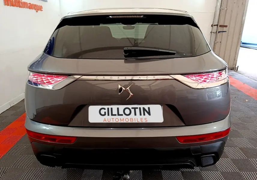 Vue arrière d’un DS7 Crossback gris foncé avec feux LED allumés et logo DS centré sur le hayon.
