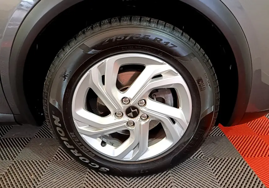 Gros plan sur la roue avant droite gris foncé du DS7 Crossback avec jante argentée et pneu hiver Pirelli.