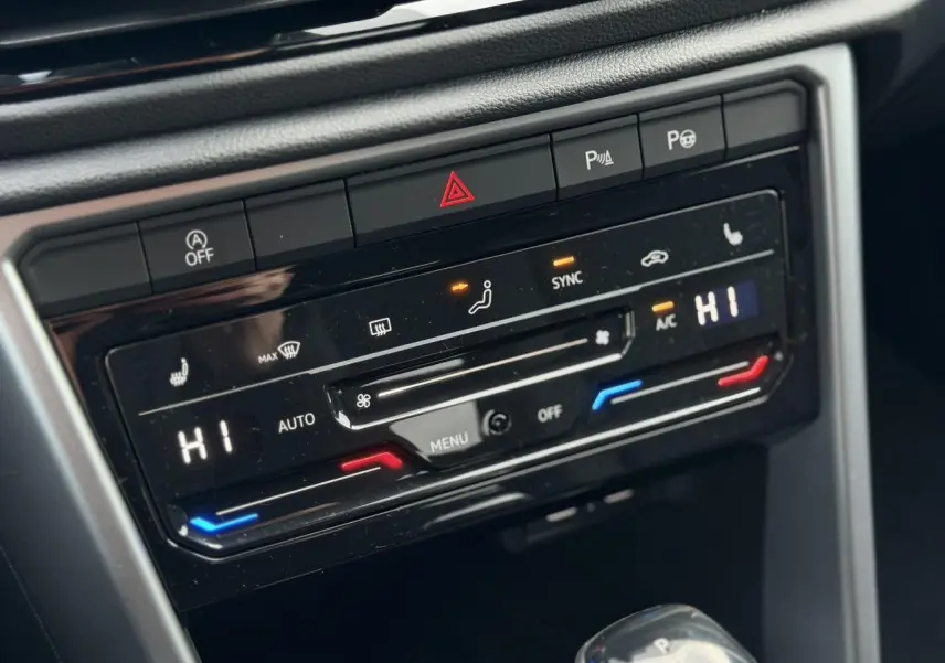 Gros plan sur la console centrale du Volkswagen T-Roc 1.5 TSI 150 DSG Life 30 Years, montrant la climatisation automatique bi-zone et les commandes chauffantes.