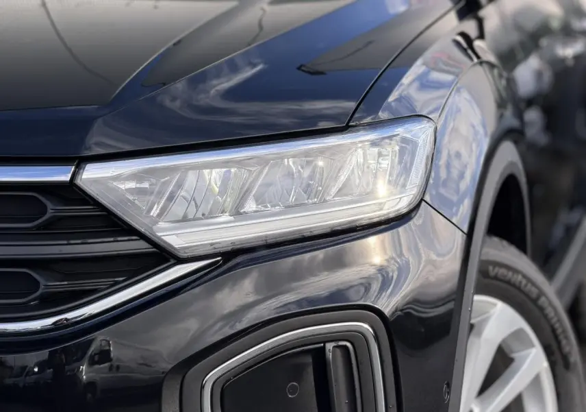 Gros plan sur l'avant droit du Volkswagen T-Roc Deep Black 2025, mettant en valeur le phare LED et la roue.