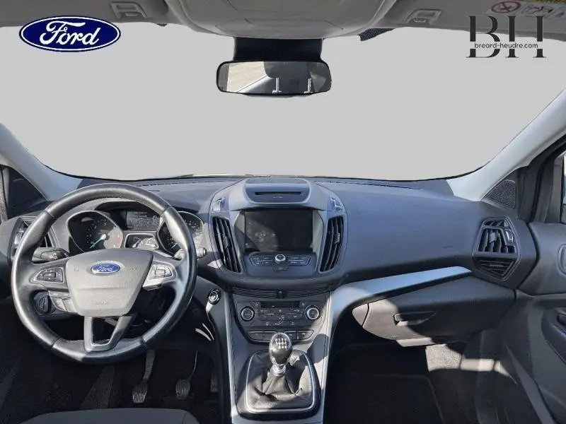 Vue intérieure frontale du tableau de bord du Ford Kuga 2018 avec volant cuir multifonction et levier de vitesse manuel.