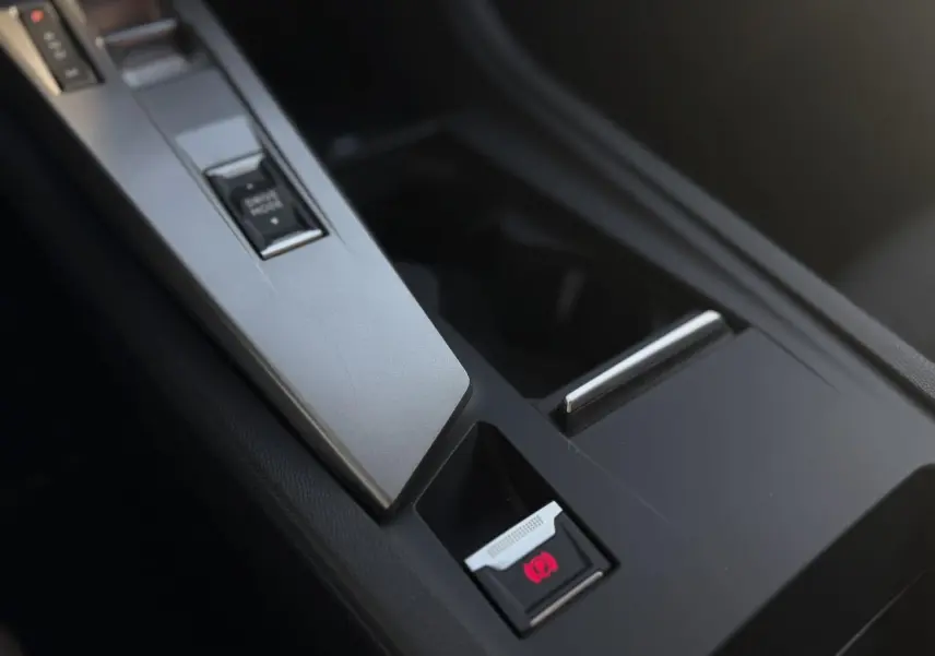 Gros plan sur la console centrale de la Peugeot 308 1.5 BlueHDI 130 Allure, avec frein de parking électrique activé.