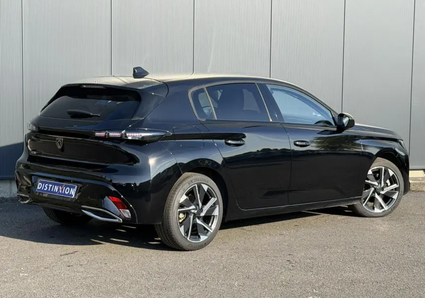 Vue 3/4 arrière droite d'une Peugeot 308 noire Perla avec jantes alliage 17 pouces et bandeau noir brillant arrière.