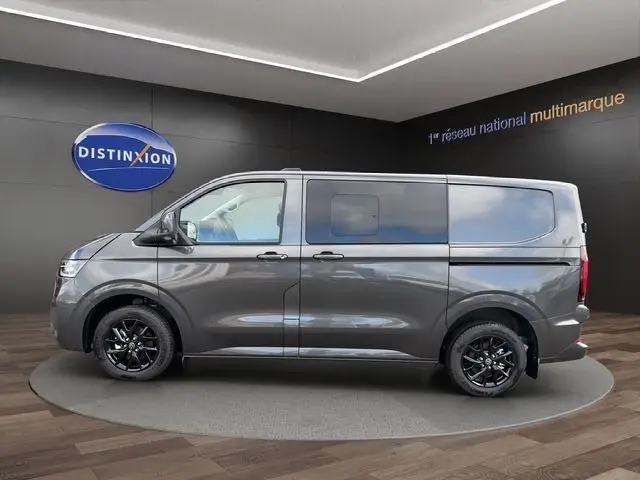 Vue de profil côté gauche d'un Volkswagen Transporter gris foncé avec jantes noires en showroom.