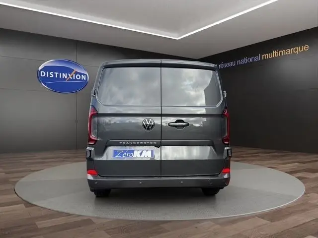 Vue arrière d'un Volkswagen Transporter gris foncé 2026, portes battantes fermées dans un showroom.