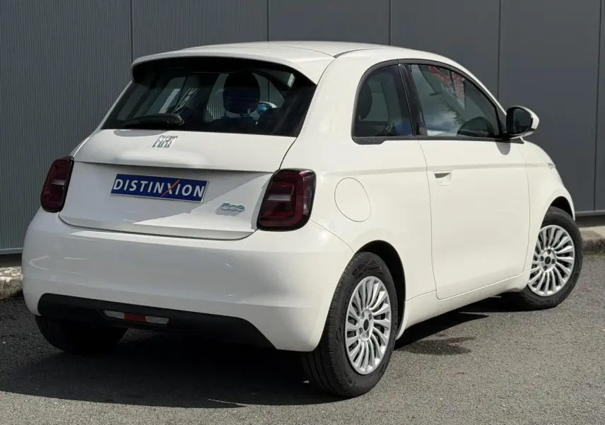 Vue 3/4 arrière droite de la FIAT 500 électrique blanc Artic avec jantes alu 16 pouces et feux arrière fumés.