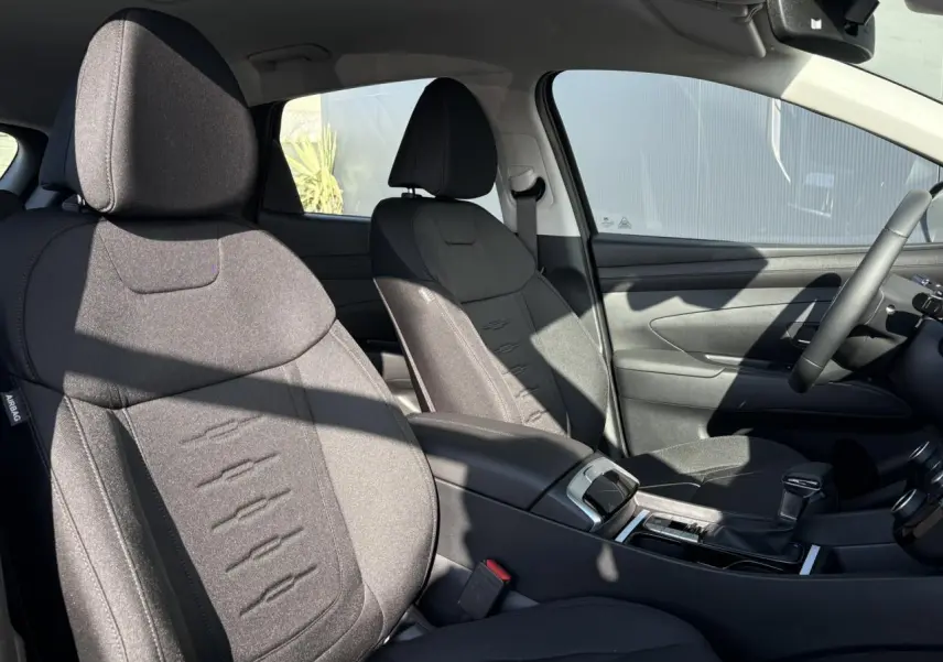 Vue intérieure côté conducteur du Hyundai Tucson 2025 avec sièges tissu noirs et console centrale moderne.