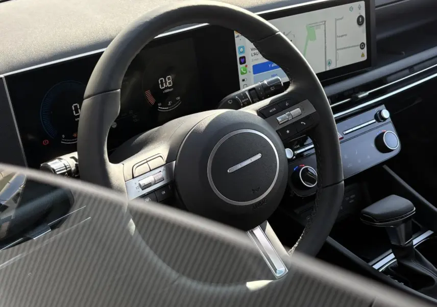 Intérieur du Hyundai Tucson 2025 vu côté conducteur, volant cuir avec commandes et écran tactile central.