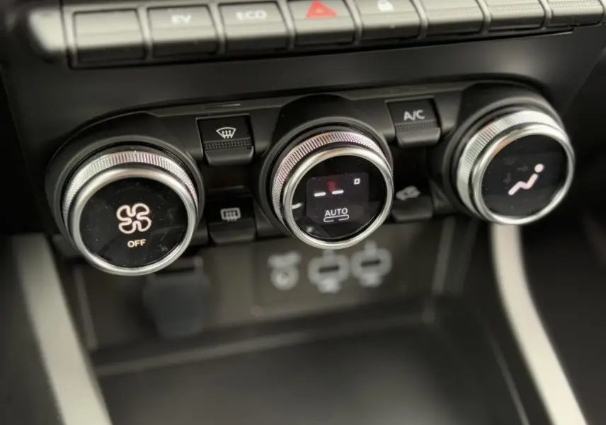 Gros plan sur les commandes de climatisation automatique du Renault Arkana E-Tech noir métal, avec réglages rotatifs et affichage digital.