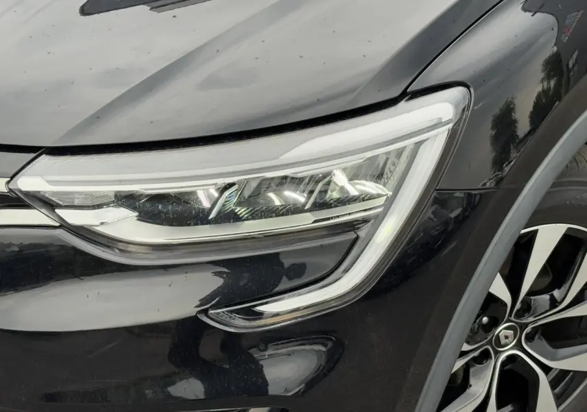 Gros plan sur le phare avant droit et la jante alliage 17" du Renault Arkana noir métal 2024.