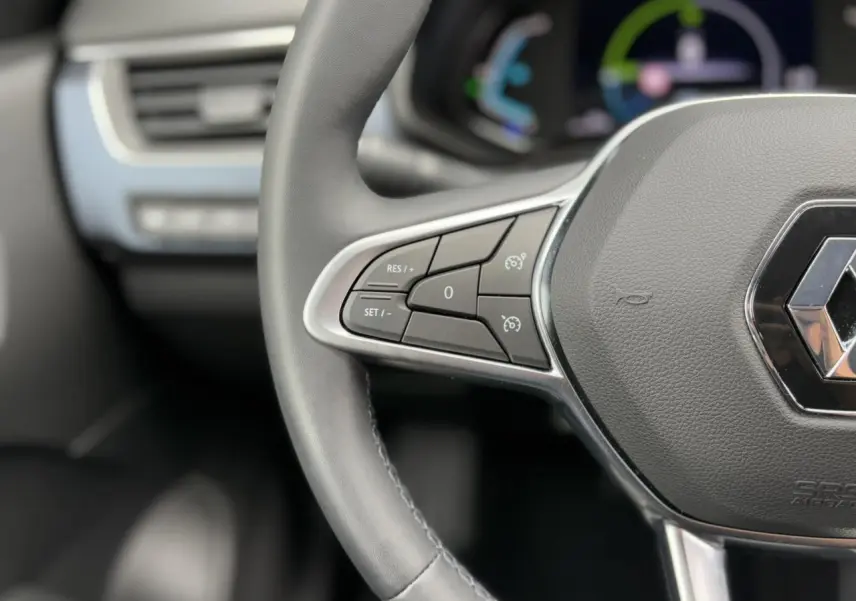 Gros plan sur le volant cuir noir du Renault Arkana E-Tech 2024 avec commandes de régulateur de vitesse intégrées.