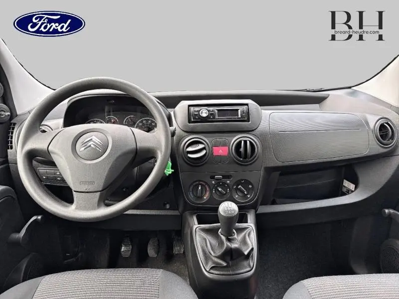 Vue intérieure frontale du tableau de bord gris et volant Citroën d'une Nemo 1.4i Confort 2013 avec boîte manuelle.