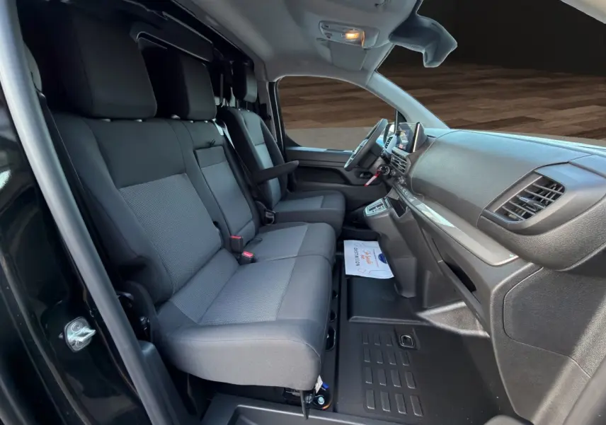 Vue intérieure côté conducteur du Citroën Jumpy noir 2026, montrant les sièges avant et le tableau de bord moderne.
