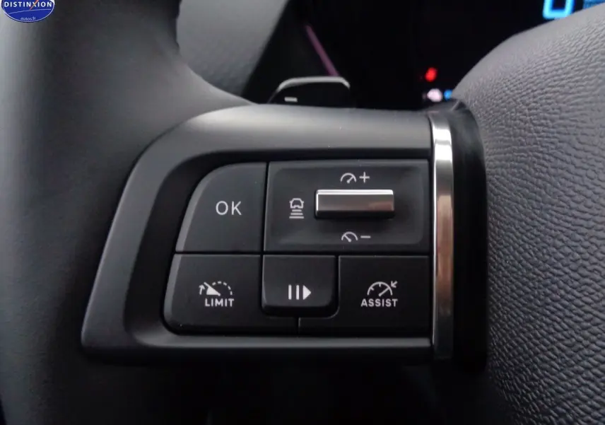 Gros plan sur les commandes au volant côté gauche de la Citroën C5 X noire hybride, avec boutons de régulateur et limiteur de vitesse.