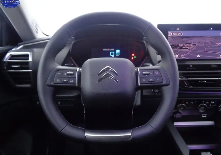 Vue centrée sur le volant cuir noir du Citroën C5 X 1.6 Hybrid 225, avec tableau de bord numérique et écran GPS.