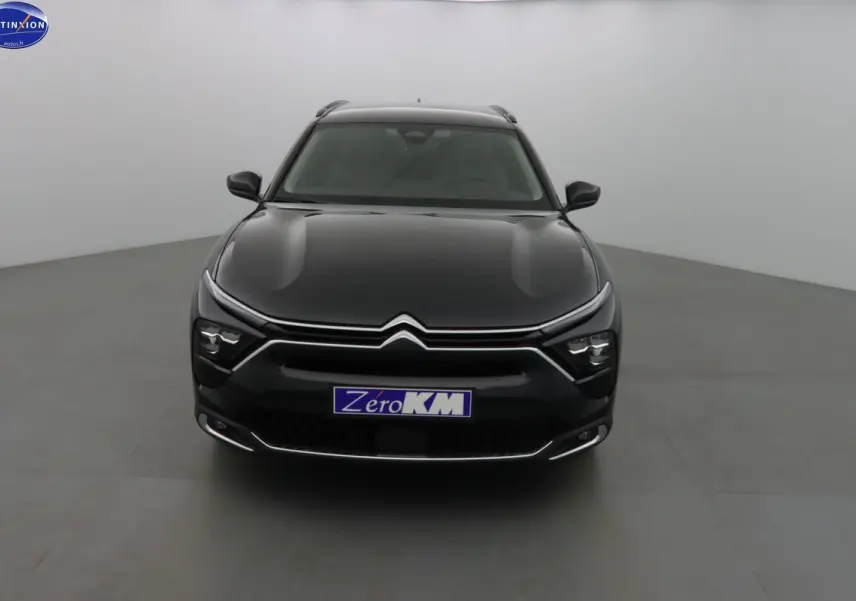 Vue frontale d'une Citroën C5 X noire métal, hybride rechargeable, avec phares LED et calandre chromée distinctive.