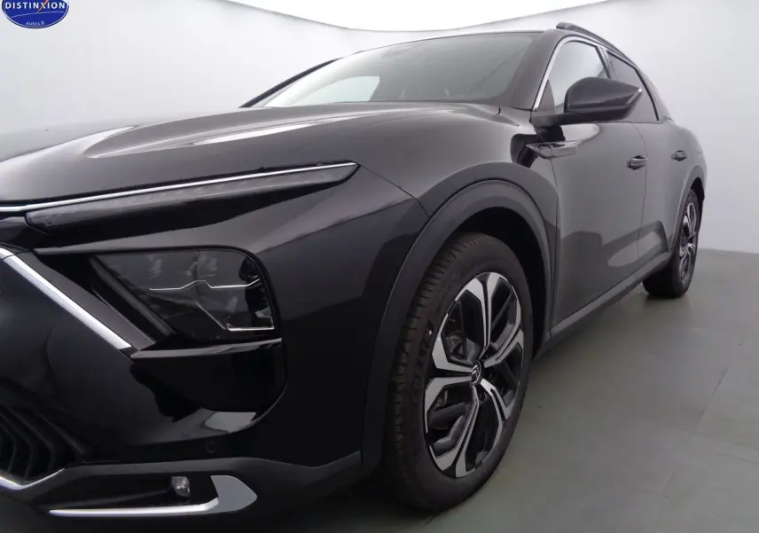 Vue 3/4 avant droit d'une Citroën C5 X noire métal avec phares LED et jantes bi-ton distinctives.