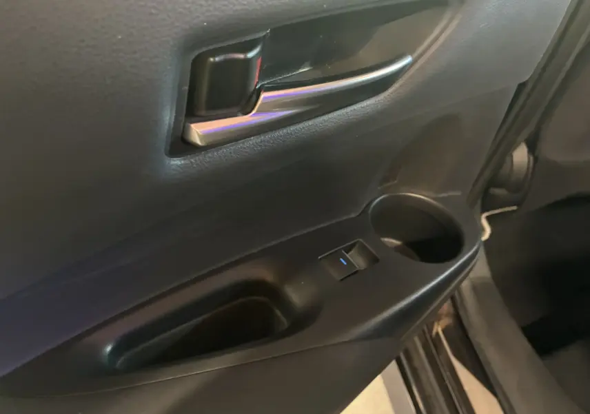 Gros plan sur la poignée intérieure et le panneau de porte côté conducteur d'une Toyota Corolla noire 2020.