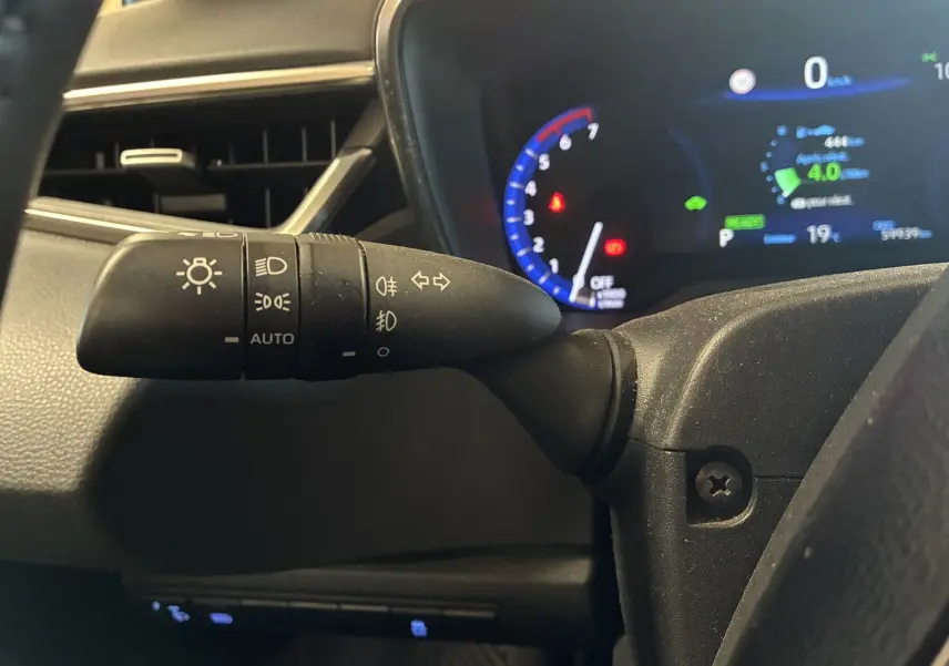 Gros plan sur la commande des phares et clignotants à gauche du volant dans le tableau de bord noir de la Toyota Corolla hybride 2020.