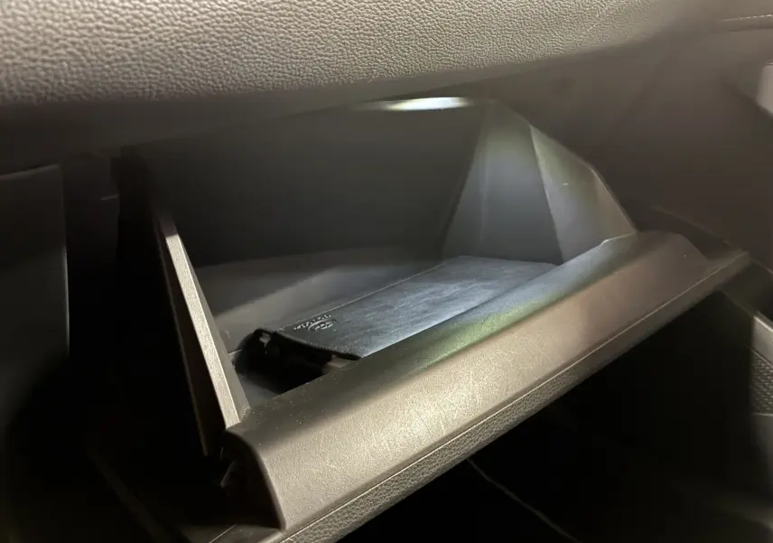 Gros plan sur la boîte à gants ouverte noire de la Toyota Corolla 1.8 122 Dynamic 2020 avec manuel à l'intérieur.