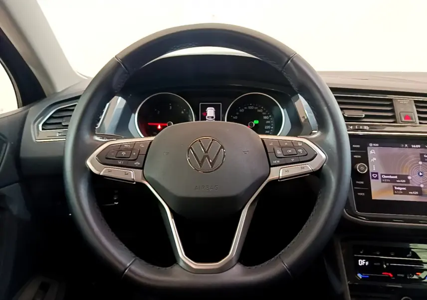 Vue frontale du volant cuir noir du Volkswagen Tiguan 2.0 TDI 150 DSG7 avec tableau de bord et écran tactile visibles.