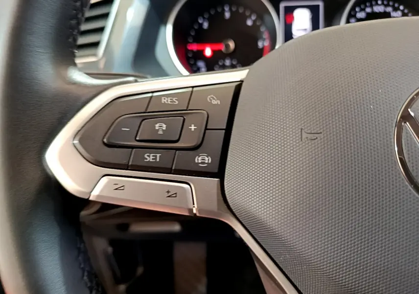 Gros plan sur le volant noir du Volkswagen Tiguan 2021 avec commandes multifonctions et tableau de bord flou en arrière-plan.