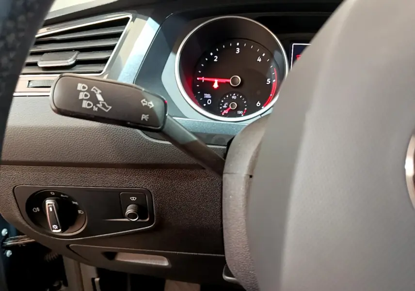 Gros plan sur le tableau de bord et le commodo gauche du Volkswagen Tiguan gris clair, avec compte-tours visible.