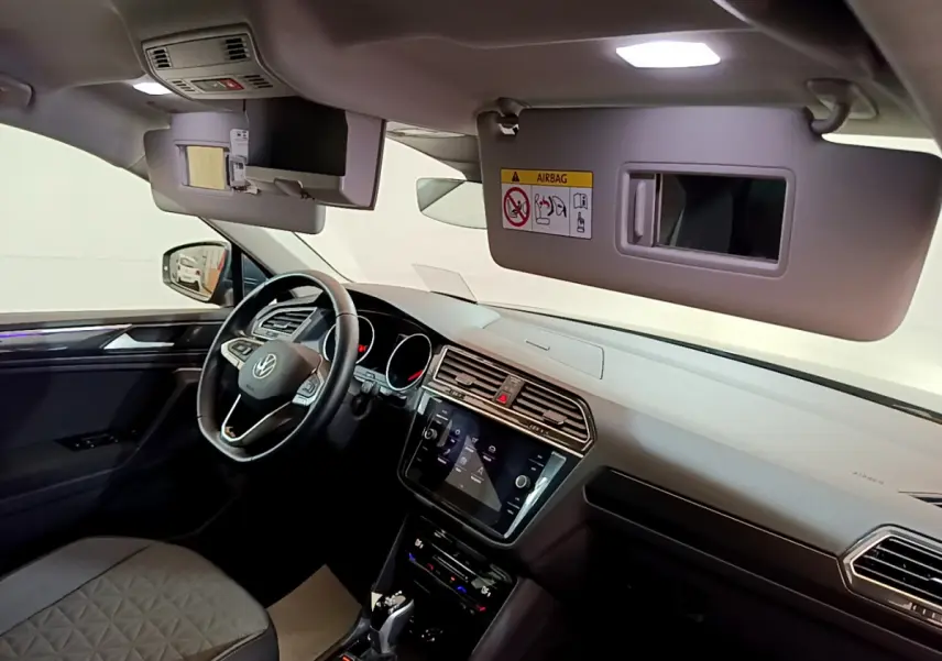 Vue intérieure côté conducteur du Volkswagen Tiguan gris clair 2021, avec tableau de bord et écran tactile visibles.