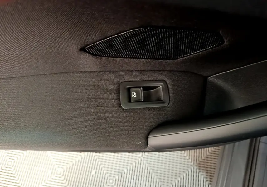Détail de la commande de lève-vitre sur la porte intérieure noire côté conducteur du Volkswagen Tiguan gris clair.