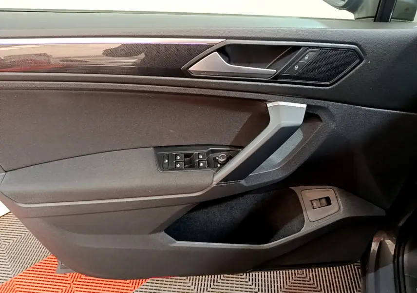 Vue intérieure côté gauche de la porte avant grise du Volkswagen Tiguan 2.0 TDI avec commandes de vitres et verrouillage.