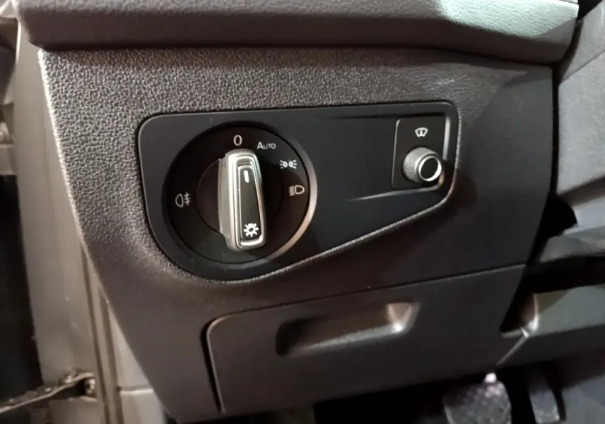 Gros plan sur le panneau de commande des phares noir à gauche du volant dans un Volkswagen Tiguan gris clair 2021.