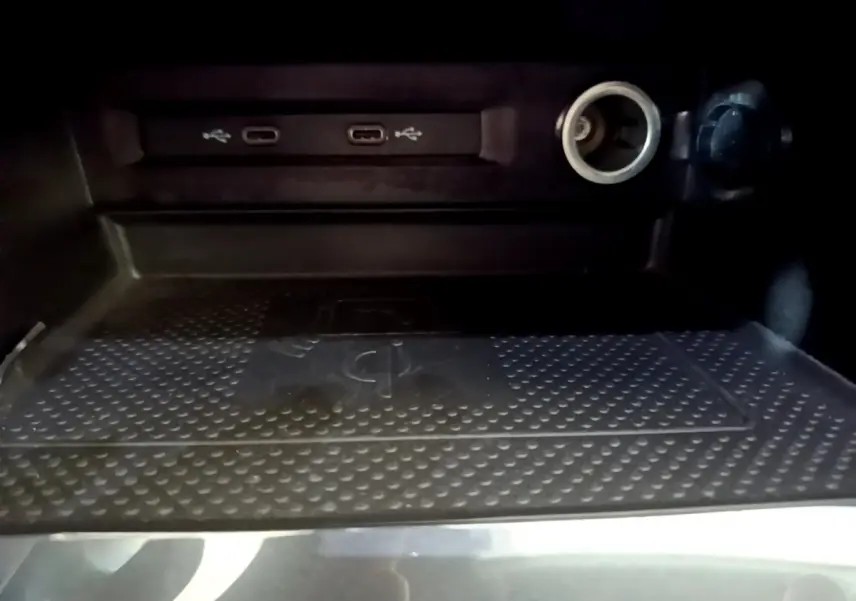 Gros plan sur la zone de recharge sans fil et ports USB-C du Volkswagen Tiguan gris clair, intérieur sombre.