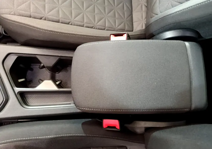 Vue plongeante sur l'accoudoir central et porte-gobelets entre les sièges tissu gris foncé du Volkswagen Tiguan 2021.
